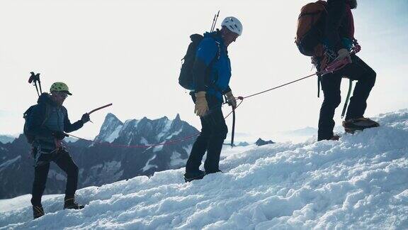 一队登山者拉着绳索向雪山山顶进发