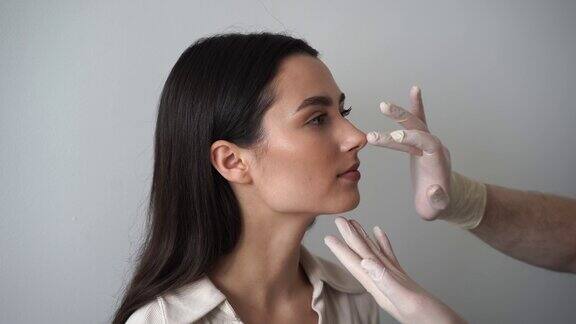 鼻整形术是一种重塑鼻子的手术目的是改变鼻子的外观改善呼吸耳鼻喉科医生在鼻中隔成形术前摸着女孩的鼻子并咨询她