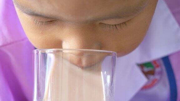 亚洲男孩用玻璃杯喝牛奶