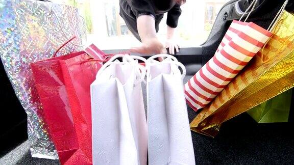 一个女人往她的汽车后备箱里装购物袋