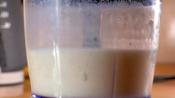 健康牛奶有机奶昔香蕉冰沙的准备过程用搅拌机搅拌