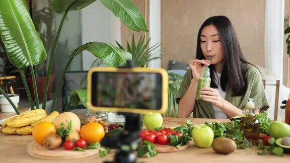 亚洲妇女用手机制作健康食品为社交媒体制作视频