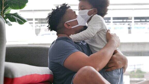 一个非洲家庭父亲带着小男孩戴着医用口罩待在家里预防新冠病毒或Covid-19的流行父亲和小男孩在一起
