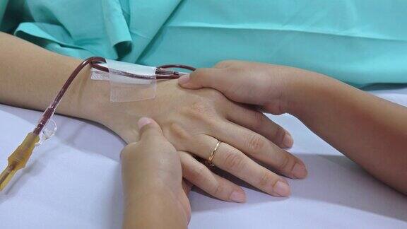在医院病床上牵着妈妈的手的小孩