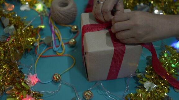 女人的手解开礼物盒上的红丝带在桌子上为圣诞节和新年