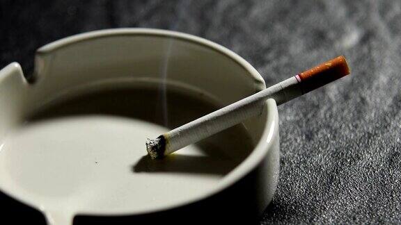 在烟灰缸上点燃并冒烟的香烟的镜头
