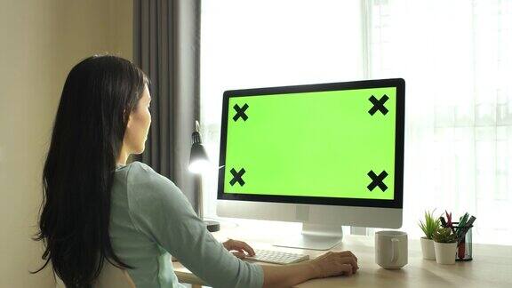 缩小在家里用绿屏电脑的女人