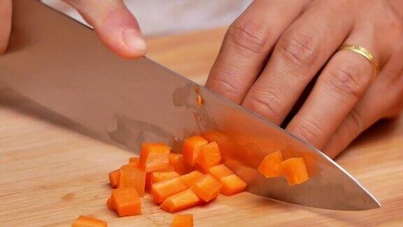 特写镜头:在砧板上女人们用刀将生胡萝卜切成小块