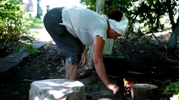 老妇人把干树枝放在村里的泥炉里