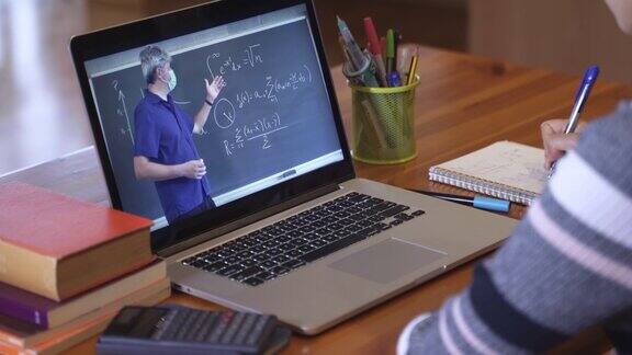 学生与戴口罩的数学老师进行教育视频通话学习由于冠状病毒大流行网上上课