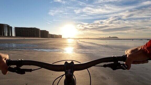第一人称视角的男人骑着自行车沿着空旷的海滩