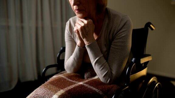 生病的妇女坐在轮椅上感到孤独、沮丧、无望在疗养院