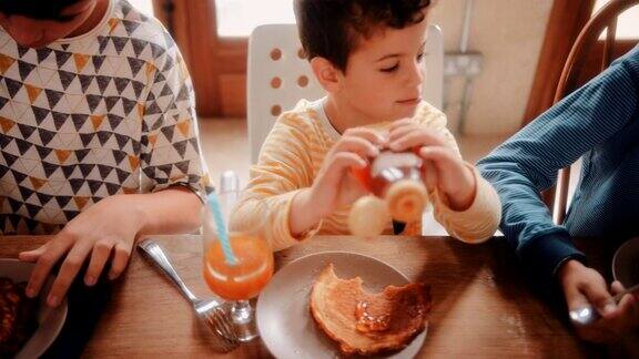 早上和兄弟姐妹们一起吃煎饼当早餐的男孩