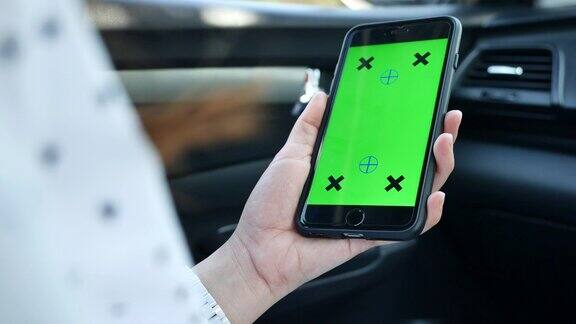 女性在绿色屏幕的汽车乘客座位上使用智能手机