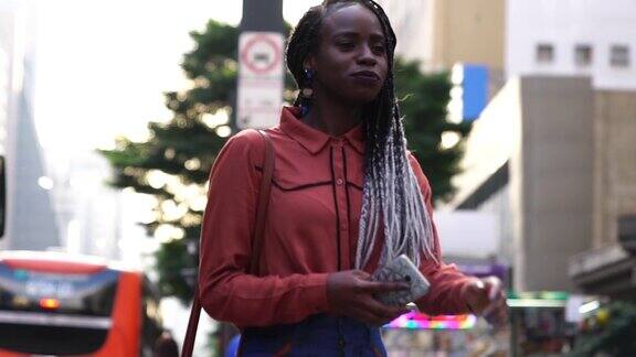 在城市中行走和使用手机的非洲裔妇女