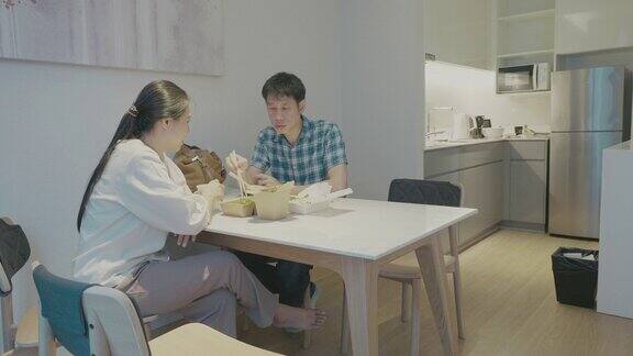 两个人另一个东亚人在他们公寓的餐桌上放一些外卖食物