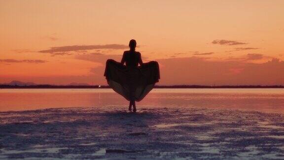 日落时在泻湖岸边散步的女人的剪影