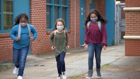 女孩们戴着口罩在小学外面跑步