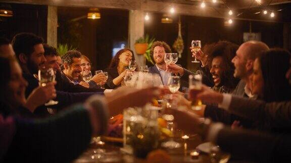 在餐厅里举办一场盛大的晚宴与少数来自不同种族的朋友一起庆祝美丽快乐的主人在晚上坐在桌子旁时提议敬酒并举起酒杯