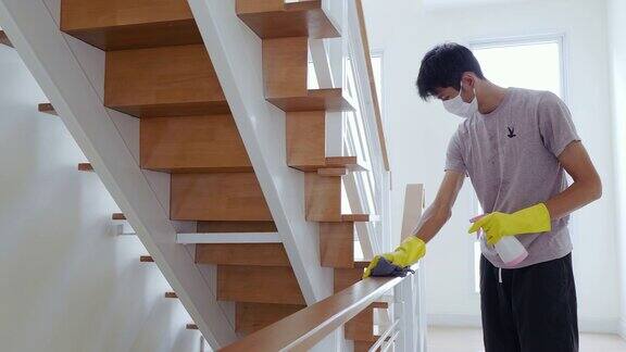 亚洲男子戴黄色手套清洁和消毒COVID-19病毒