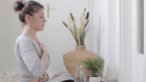 女人盘腿坐在家里做呼吸练习