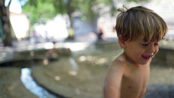 小孩在公园玩水小男孩在喷泉享受夏日穿着儿童泳衣简短