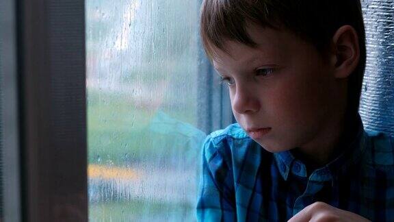 男孩在雨中看着窗外很伤心