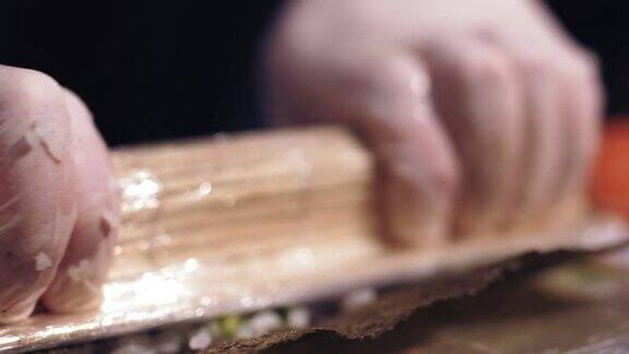 日本传统食物特写镜头在寿司吧或餐厅的专业厨房制作寿司卷寿司厨师正在用原料将海苔包起来