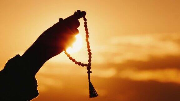 手握念珠对着天空和夕阳真诚的祈祷和冥想