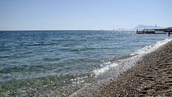 海浪在卵石滩上的特写与反射的太阳在海浪地中海