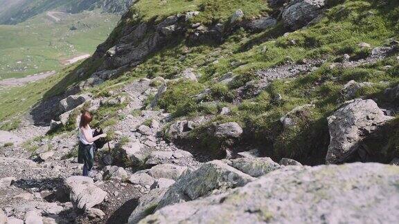一位年轻的女性徒步旅行者带着照相机爬山罗马尼亚喀尔巴阡山脉的transagarasan