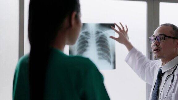 在医院的放射科一名成熟的男医生和一名年轻的女病人正在检查胸部x光片和肺部扫描