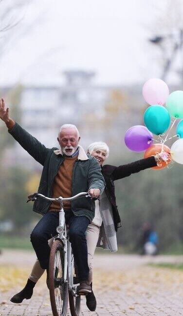 垂直视频无忧无虑的老夫妇在秋天的一天骑自行车