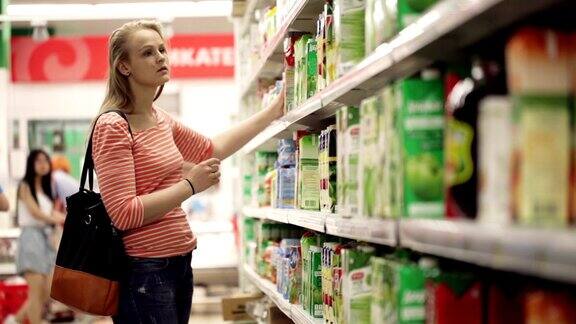 女人在超市挑选果汁