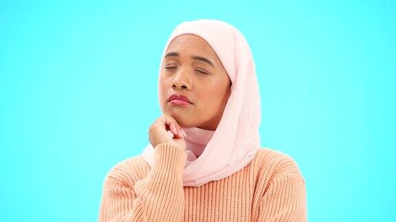 穆斯林妇女在工作室里思考和想法手放在下巴上的模型广告或选择伊斯兰女性戴着头巾和表情符号在蓝色背景下思考、怀疑或困惑