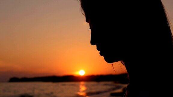 《日落时海滩上悲伤孤独的女人
