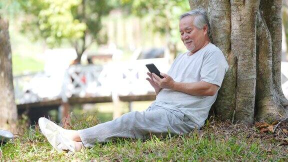 亚洲老年人在公园玩手机游戏