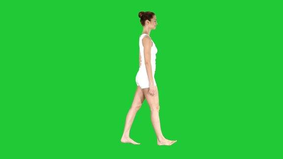一名女性赤脚走在绿色屏幕上的白色衣服色度键