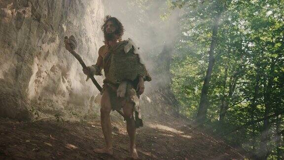 戴着兽皮的原始穴居人手持石锤走出洞穴四处张望探索史前森林准备狩猎动物猎物尼安德特人进入丛林狩猎
