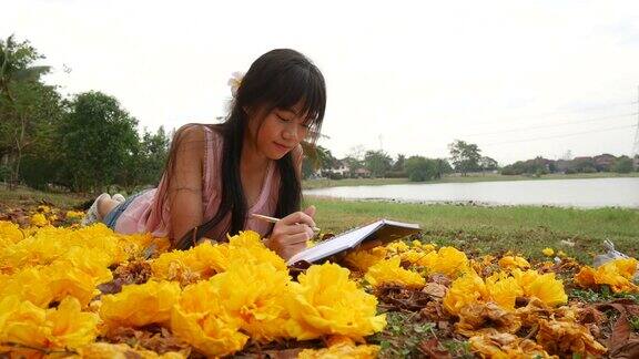 亚洲女孩躺在草地上看书