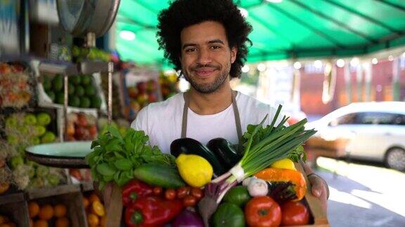一名黑人男子在果蔬市场工作手里拿着装满新鲜食物的美味篮子对着镜头微笑
