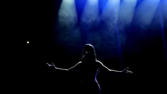 那位美丽的歌手在黑暗中在舞台上唱歌