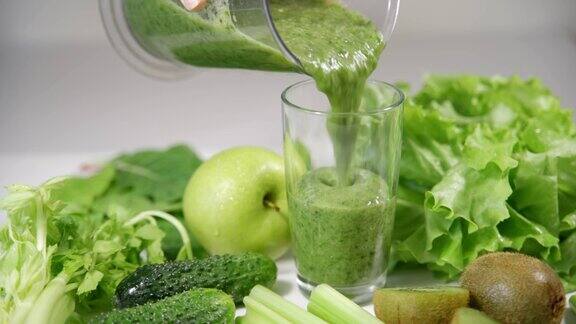 从搅拌机里倒绿色果汁到玻璃杯