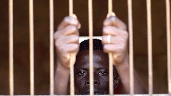 移民、圈养、权利悲伤的年轻非洲人在监狱里-慢镜头