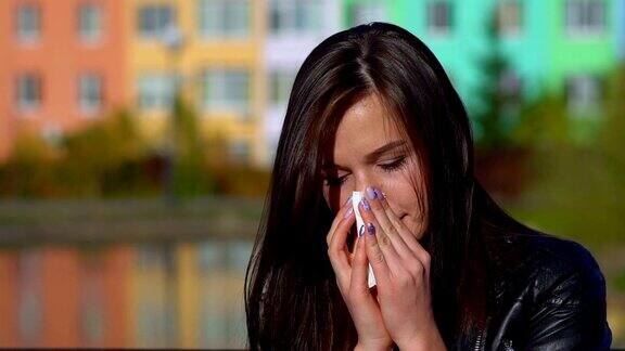 年轻漂亮的女孩在街上感冒了用餐巾擦了擦鼻子
