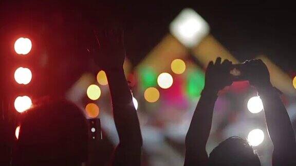 人群在音乐会上举起双手剪影为音乐节欢呼的人群