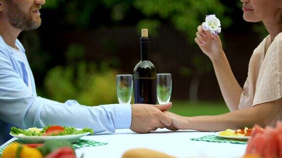 爱情告白的中年男子与女子在浪漫晚餐上手牵着手