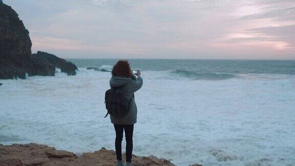 穿着灰色羊毛衫的女孩在阴天寒冷的天气里独自走在空旷的海边