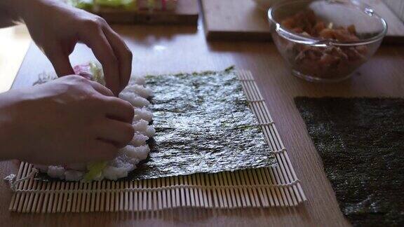 女孩自制寿司手把米饭放在海苔、黄瓜、蟹条和奶酪上