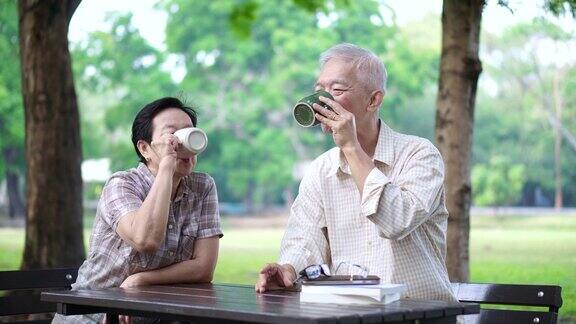 亚洲退休老年夫妇在公园喝咖啡和看书
